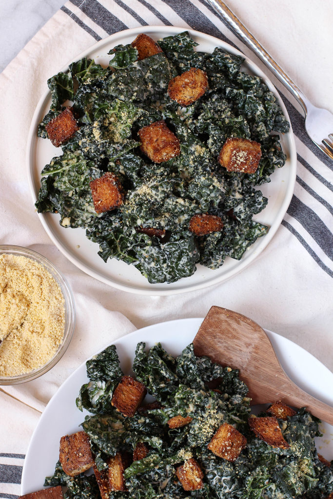 Vegan Kale Caesar Salad with tangy garlic tahini dressing, cashew parmesan, and whole grain croutons.